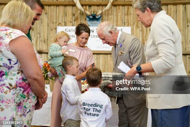 Prince Charles, Prince of Wales is presented with wool rugs by Dusty Smith and his brother George , the children of Matt and Pippa Smith, as he...