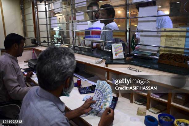 Foreign currency dealer counts US dollar notes at a currency market in Karachi on July 19, 2022.