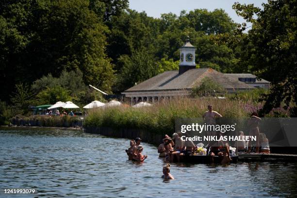 People wade in the Serpentine lake to cool off in Hyde Park, west London, on July 19, 2022 as the country experiences an extreme heat wave. Britain...