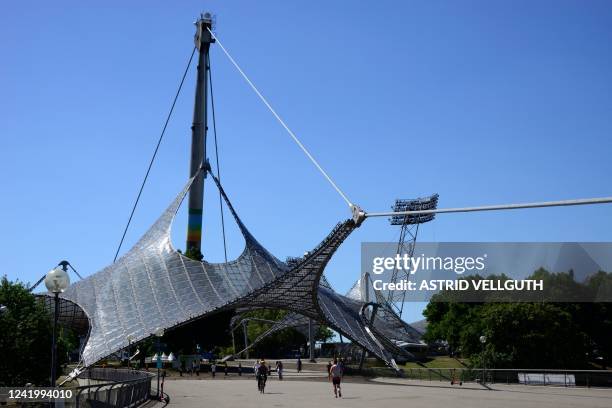 People cross the footbridge towards the Olympic Stadium with its tent roof construction at the Olympic Park in Munich, southern Germany on July 17,...