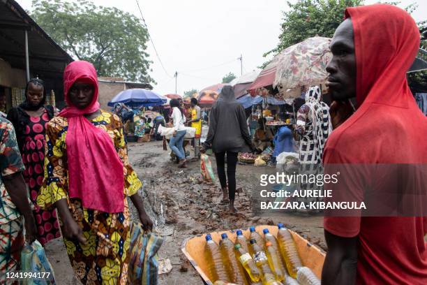Vendor selling bottles of cooking oil pushes a wheelbarrow in a small alley at the market in Dembe, a district in N'Djamena, on July 16, 2022.