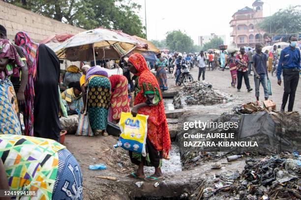 An elderly lady passes over a gutter to see the fruit and vegetable stalls of vendors at the market in Dembe, a district in N'Djamena, on July 16,...