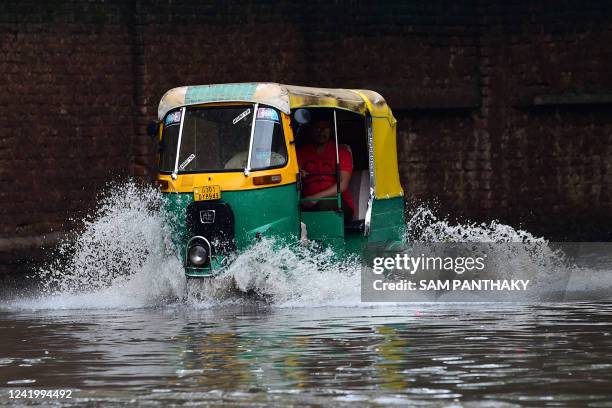 An autorickshaw wades across a flooded street after heavy rains in Ahmedabad on July 19, 2022.