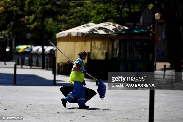 Street sweeper woman walks along the street in L'Hospitalet del Llobregat, near Barcelona, on July 19, 2022. - Spain, which has already seen its...