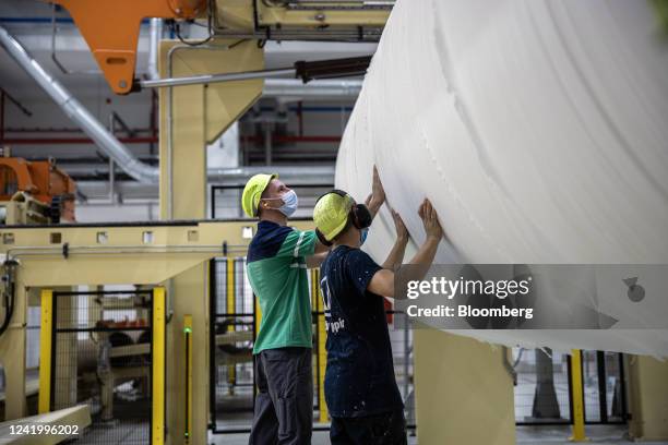 Employees handle a spool of paper at the Vajda Papir Ltd. Hygienic paper factory in Dunafoldvar, Hungary, on Tuesday, July 19, 2022. Hungary's...