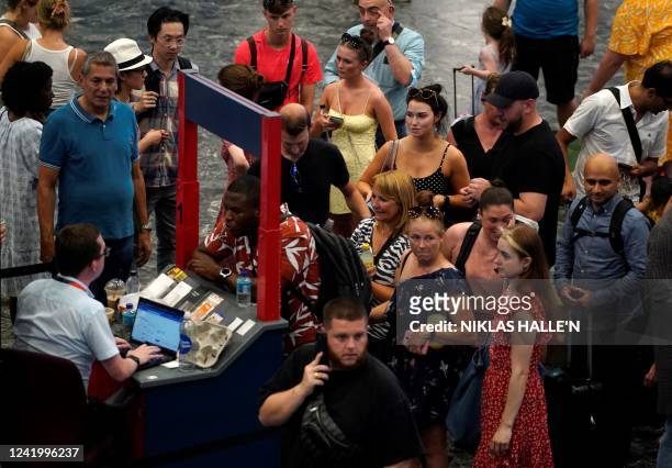 Customers queue at a help desk at Euston train station in central London, on July 19 as services were cancelled due to a trackside fire, and as the...