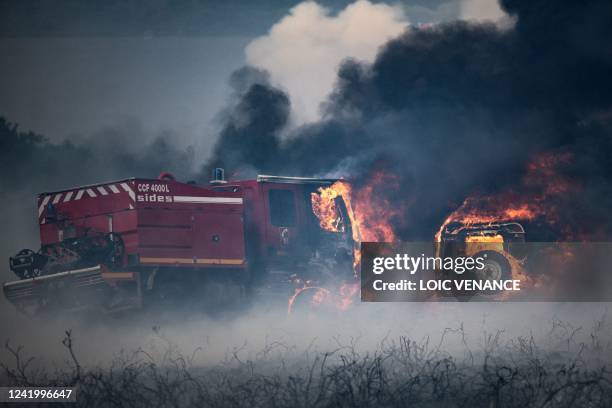 Picture taken on July 19, 2022 shows firefighter trucks burning during a wildfire on the Mont d'Arrees, outside Brasparts, western France. - The fire...