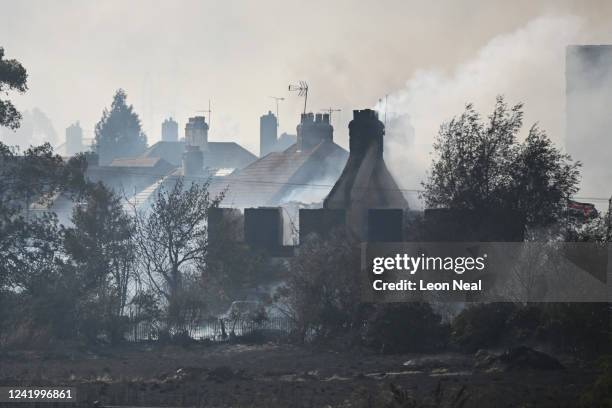 Union Flag flies amongst the smouldering ruins of houses as fire services tackle a large blaze on July 19, 2022 in Wennington, England. A series of...