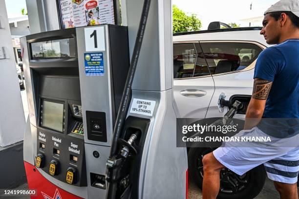 Person pumps gas into his car at a gas station in Miami, Florida, on July 19, 2022. - US gasoline prices have fallen from historic highs earlier in...