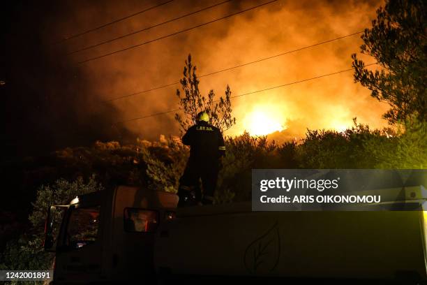 Firefighter stands on a truck as a wildfire rages in Anthousa, north of Athens, on July 19, 2022. The Greek civil protection called on July 19 for...