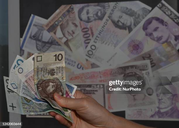 Person holds banknotes of the Polish Zloty in front of a sticker showing various currencies. On Tuesday, July 19 in Rzeszow, Podkarpackie...