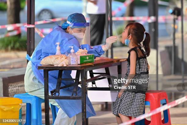 This photo taken on July 19, 2022 shows a health worker taking a swab sample from a child to be tested for the Covid-19 coronavirus at a swab...