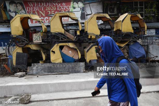 Pedestrian walks past tricycles, locally known as padyak, for sale in a neighbourhood in Manila on July 20, 2022.