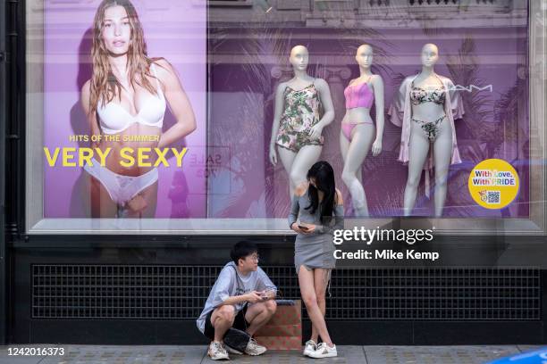 Two people interact with advertising photographs featuring models in the shop windows of exclusive lingerie store Victoria's Secret on Bond Street on...