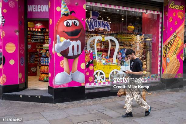 Man walks his dog past the American Candy Shop at Leicester Square on 12th July 2022 in London, United Kingdom. London is one of the worlds leading...