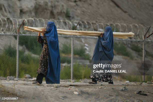 Burqa-clad women carry logs of wood near the Qale'H-Ye-Balahissar fortress in Kabul on July 20, 2022.