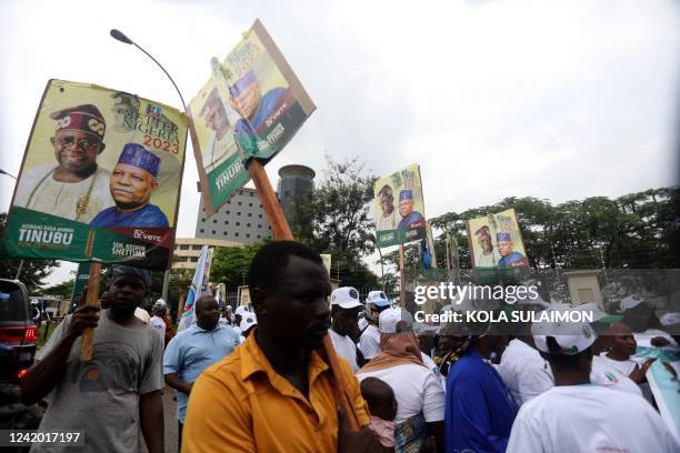 Supporters of Nigerias All Progressive Congress ruling party hold posters of APC presidential and vice-presidential candidates outside a party...