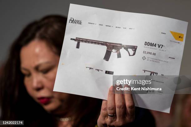 Sen. Tammy Duckworth holds up an advertisement from Daniel Defense while talking to reporters following a hearing about the mass shooting in Highland...