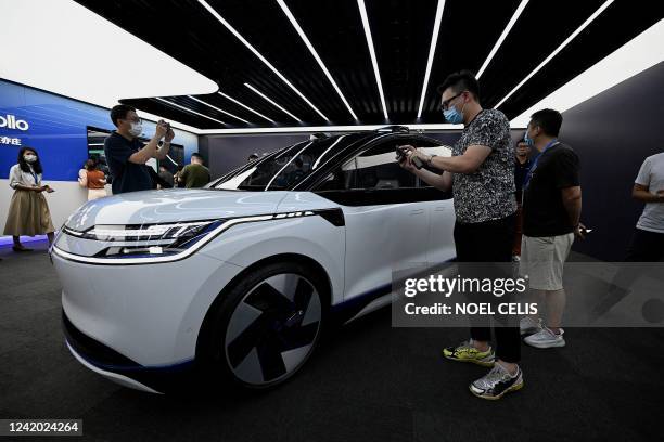 This picture taken on July 20, 2022 shows journalists looking at Baidu's Apollo RT6 next-generation autonomous vehicle during its unveiling in...