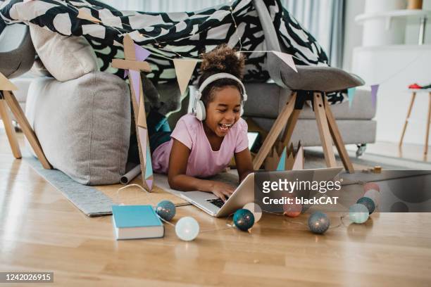 meisje dat laptop onder haar huis-gemaakte tent binnen de woonkamer gebruikt - camping games stockfoto's en -beelden