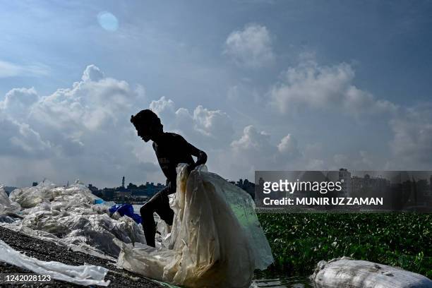 Worker dries used plastic bags in the banks of the Buriganga River in Dhaka on July 21, 2022.