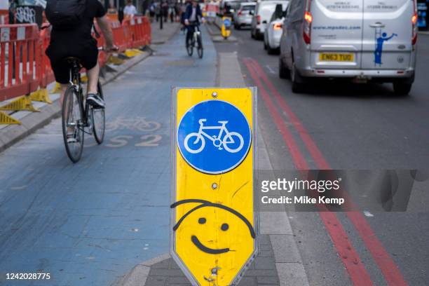 Cyclist passes on a happy face on a cycle lane superhighway sign in Aldgate on 14th July in London, United Kingdom. A cycle Superhighway is a long...