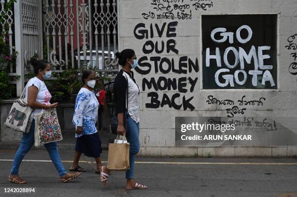 Man rides a bicycle walk past slogans painted on a wall against the government near the president's office residence in Colombo on July 21, 2022. Sri...