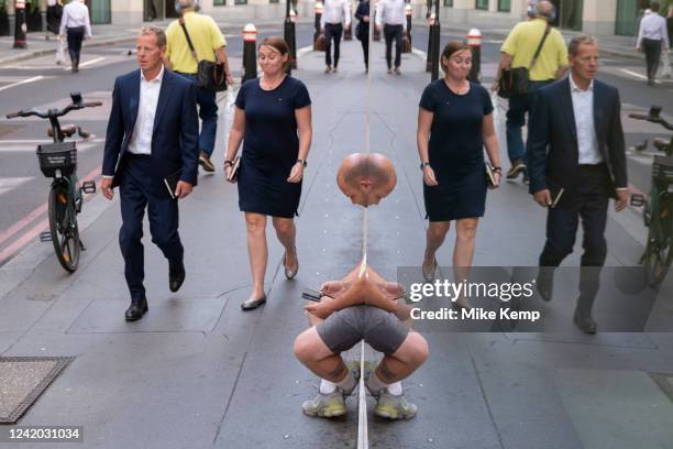 Amusing reflection giving a man the appearance of having a distorted mirror image of his body on 14th July in London, United Kingdom.