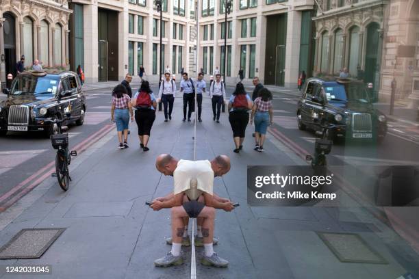 Amusing reflection giving a man the appearance of having a distorted mirror image of his body on 14th July in London, United Kingdom.