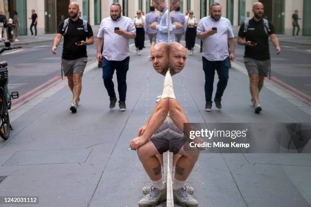 Amusing reflection giving a man the appearance of having a distorted mirror image of his body on 14th July in London, United Kingdom.