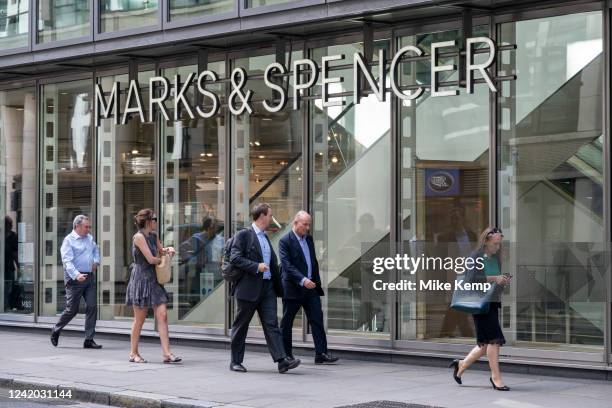 People pass a sign for department store and supermarket chain Marks and Spencer in the City of London on 14th July in London, United Kingdom. Marks &...