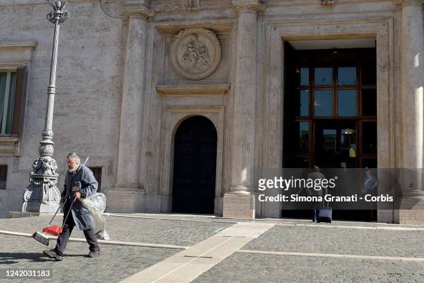 Cleaner with a broom and dustpan cleans the entrance to Montecitorio, seat of the Chamber of Deputies, on July 21, 2022 in Rome, Italy. Italian Prime...