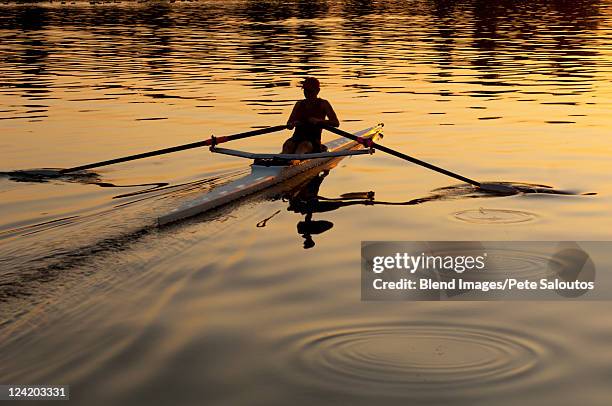 person rowing sculling boat on river - single scull stockfoto's en -beelden