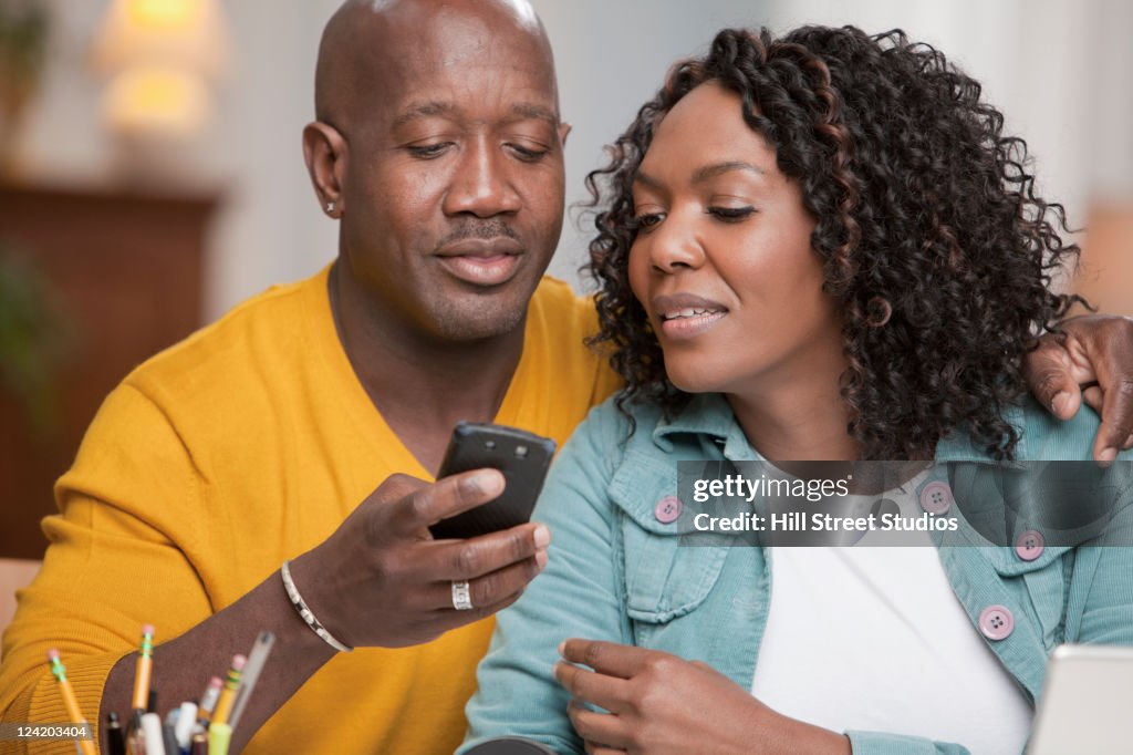 Smiling African American couple using cell phone together