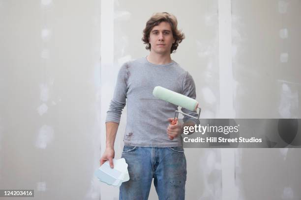 caucasian man holding color swatches and paint roller - holding paint roller stock pictures, royalty-free photos & images