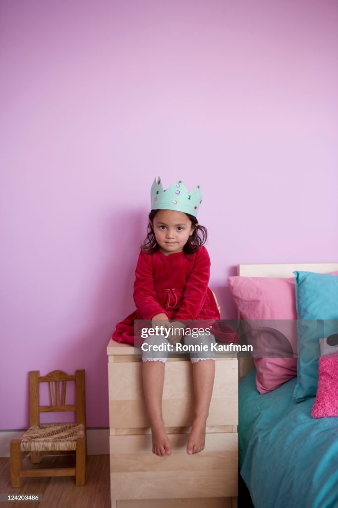 Girl in crown sitting on night table