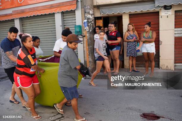 Residents of the Complexo do Alemao favela carry the corpse of a dead man during a police raid in Rio de Janeiro, Brazil, on July 21, 2022. At least...