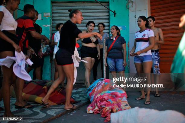 Bodies of dead men are seen covered with blankets after residents carried them to Complexo do Alemao's main street to be taken to a hospital, during...