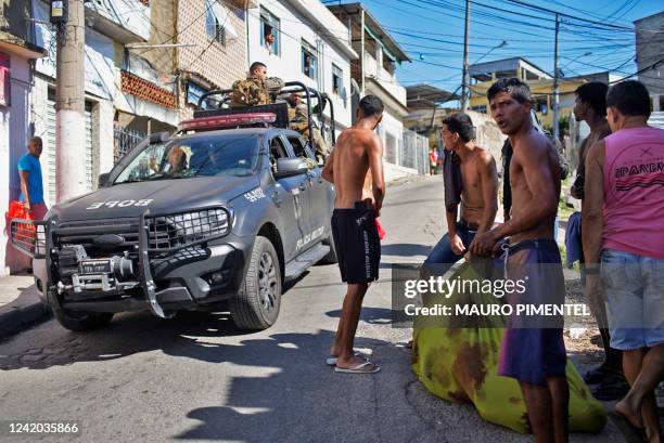 Police truck passes next to residents of the Complexo do Alemao favela carrying the corpse of a dead man during a police raid in Rio de Janeiro,...