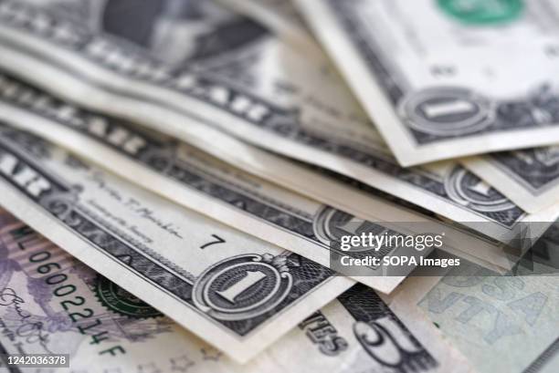 In this photo illustration, one and five dollar bills seen on display.