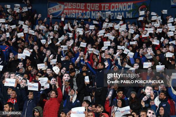 Fans of Nacional hold masks with an image of Uruguayan football star Luis Suarez and placards reading #SuárezANacional as part of a campaign to try...