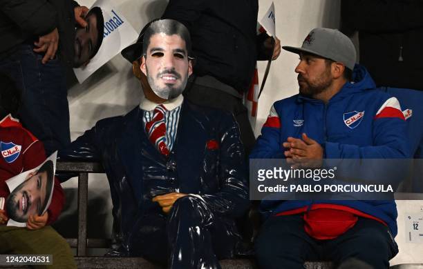 Fan of Nacional looks at a statue of popular tango singer-songwriter Carlos Gardel with a mask with an image of Uruguayan football star Luis Suarez...