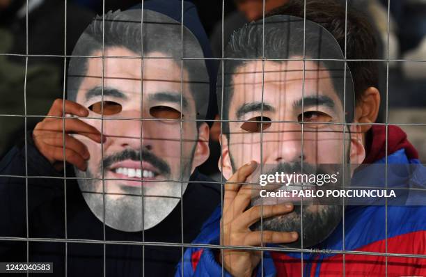 Fans of Nacional hold masks with an image of Uruguayan football star Luis Suarez during a campaign to try to convince him to return to the club,...