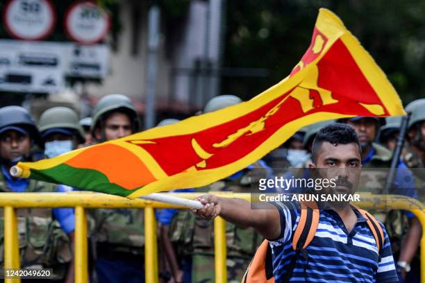 Demonstrator waves a Sri Lankan flag near police barriacdes during a protest march towards the Presidential secretariat office against Sri Lankan...
