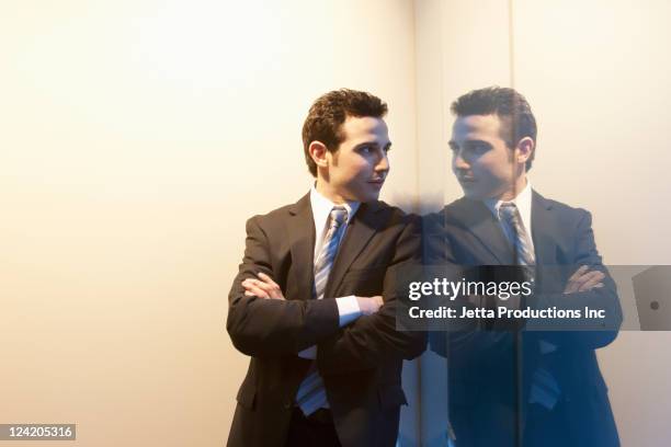 caucasian businessman leaning on wall with arms crossed - よそいきの服 ストックフォトと画像