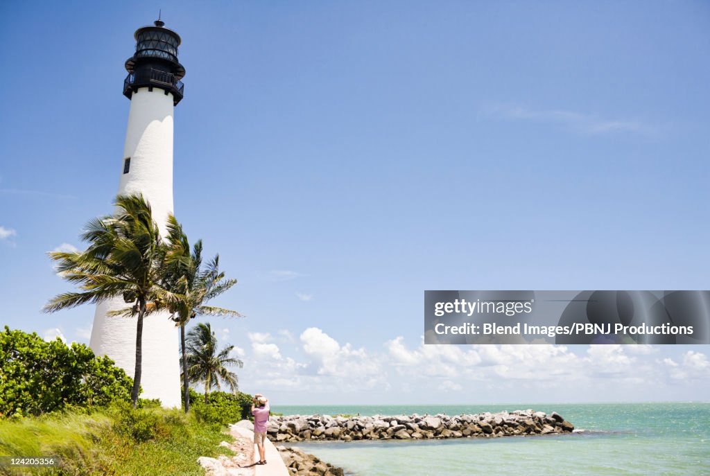 Lighthouse and tropical palm trees near ocean