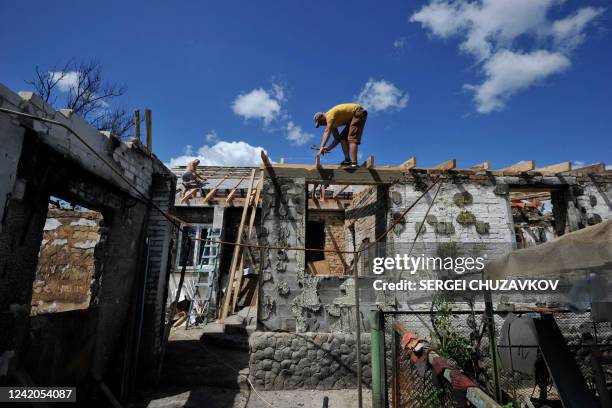 Volunteer repairs the roof of the house of an elderly woman, after being destroyed by shelling in the village of Zalissya, Kyiv region, on 22 July...