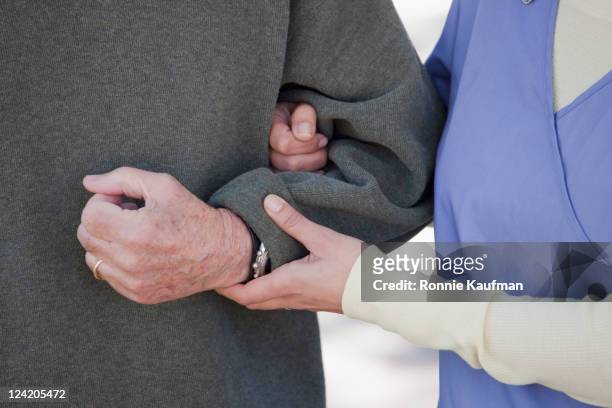 nurse supporting senior man - arm in arm stock pictures, royalty-free photos & images