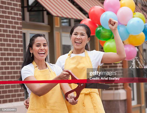 excited business partners cutting ribbon on grand opening - grand opening event stock pictures, royalty-free photos & images