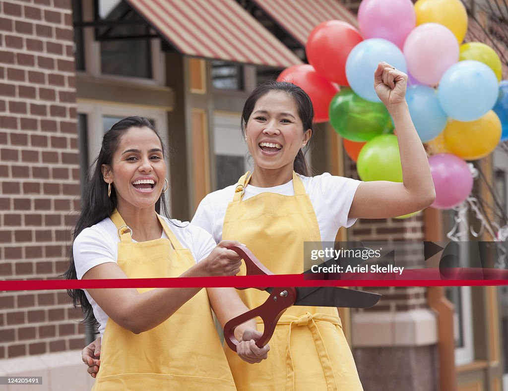 Excited business partners cutting ribbon on grand opening